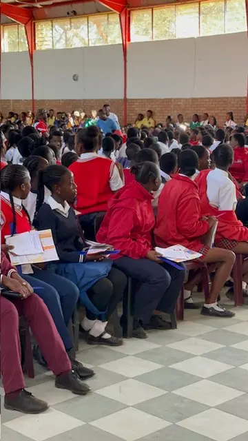 Learners in school uniform seated with career information booklets