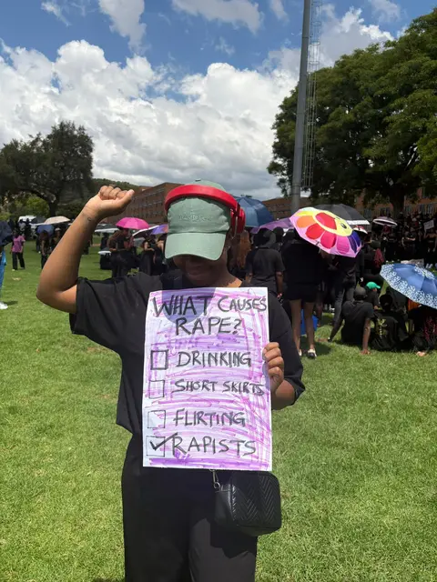 A protester raising a fist with a placard challenging rape myths